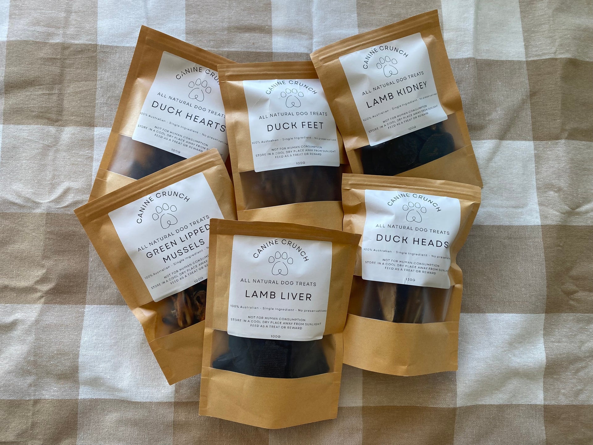 Five packages of dog treats on a checkered fabric background